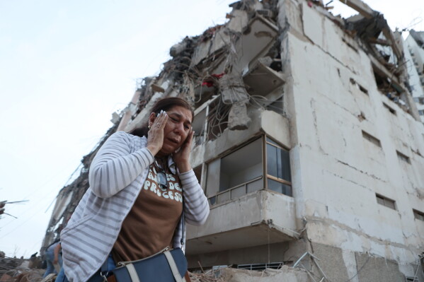 A woman walks past a building damaged during an earthquake in La Guaira, Venezuela, Thursday, June 25, 2026. (AP Photo/Pedro Mattey)