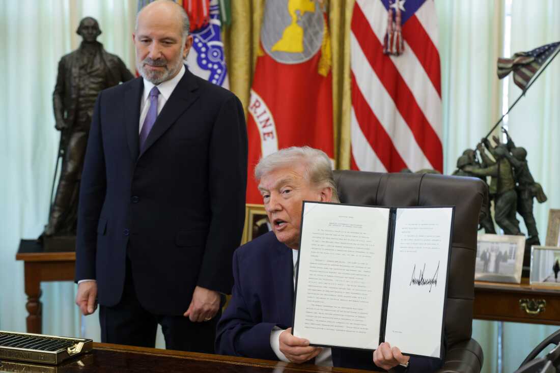 President Trump holds up an executive order to limit mail-in voting as Commerce Secretary Howard Lutnick looks on in the White House’s Oval Office in March.