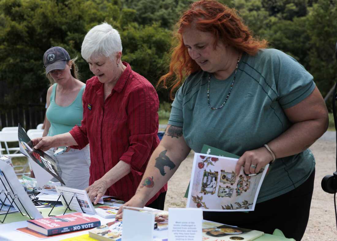 Zinn Education Project’s Deborah Menkart, in red shirt, shares examples of banned books and other reading materials during the America 433 pop-up event at Harpers Ferry National Historical Park on June 19.