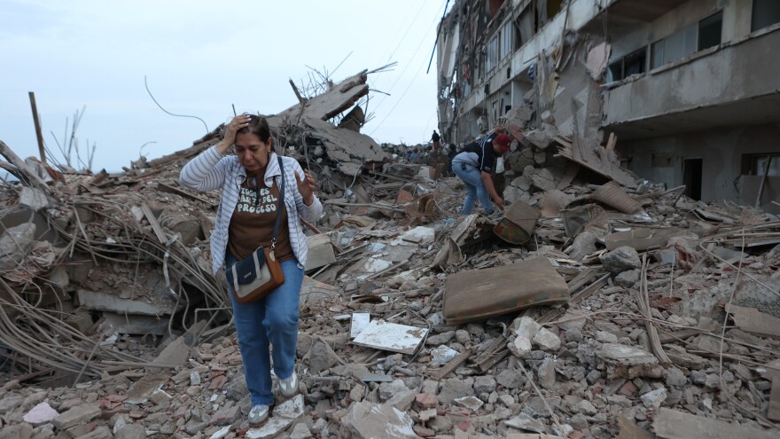 Residents walk amid the rubble of a building damaged in earthquakes the previous day in Catia La Mar, Venezuela.