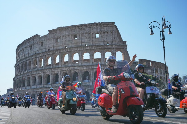 Vespa enthusiasts parade in front of the Colosseum during celebrations for the 80th anniversary of the Vespa scooter, in Rome, Saturday, June 27, 2026. (AP Photo/Alessandra Tarantino)