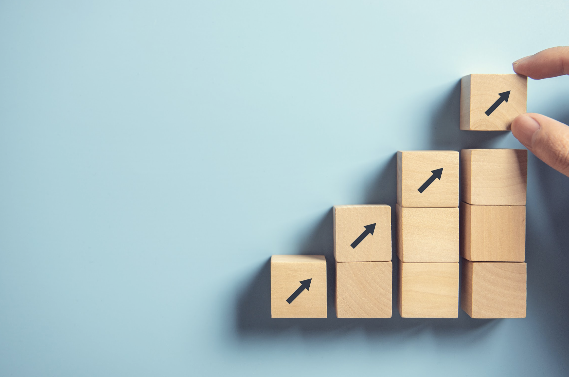 An ascending stack of wooden blocks with arrows pointing up.