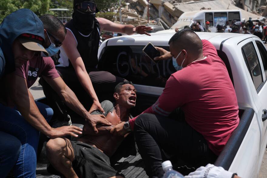 Residents transport a man rescued from the rubble three days after earthquakes struck, in La Guaira, Venezuela, Saturday, June 27, 2026.