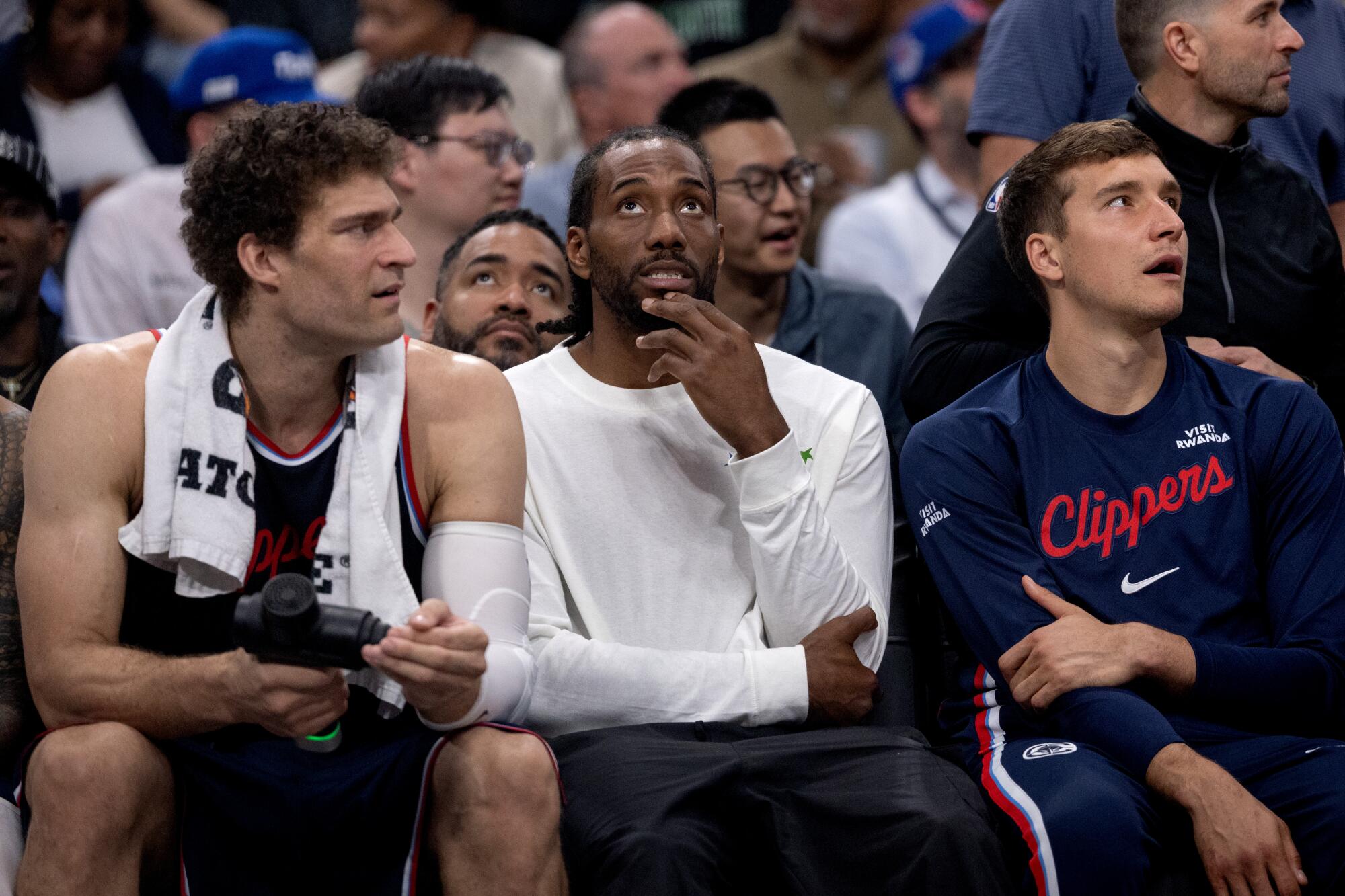 Kawhi Leonard sits on the bench between Clipper teammates Brook Lopez, left, and Bogdan Bogdanovic during a game last season.
