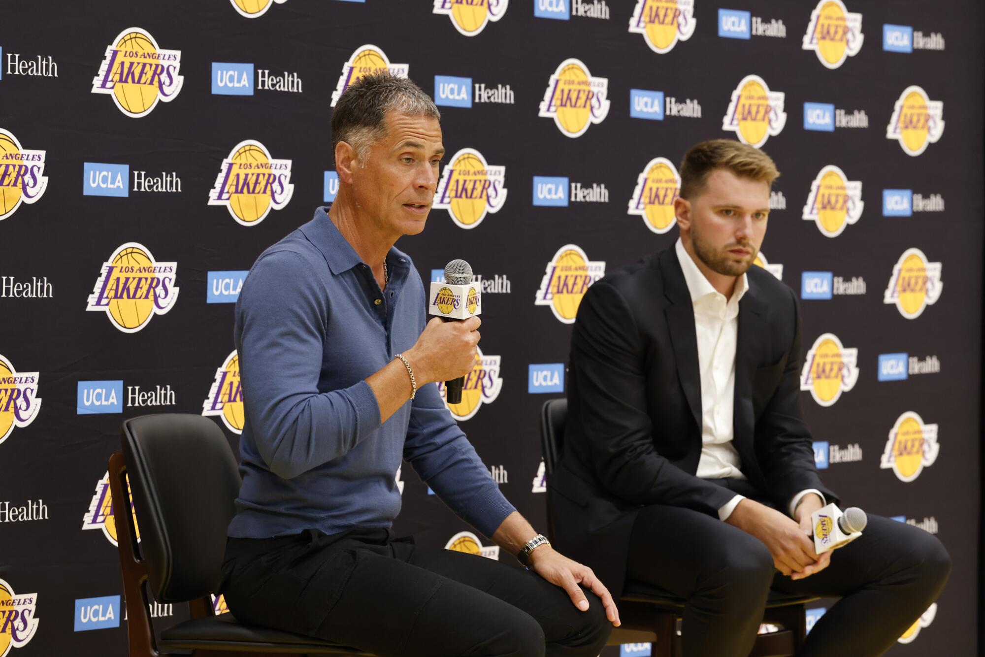 Lakers GM Rob Pelinka, left, talks to reporters during the introductoy news conference for Luka Doncic, right.