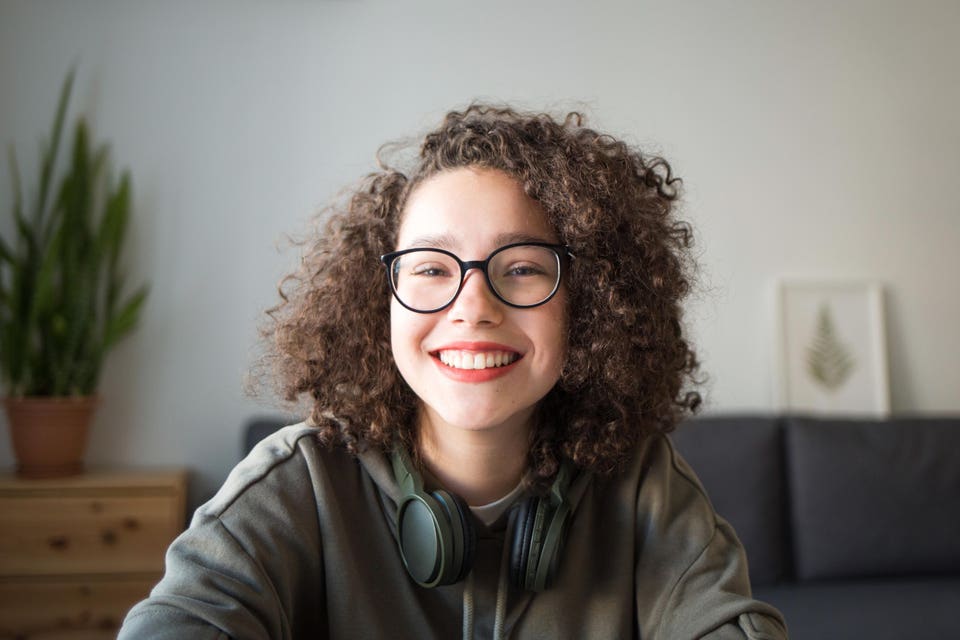 girl looks at camera and smiles. student talks over Internet.