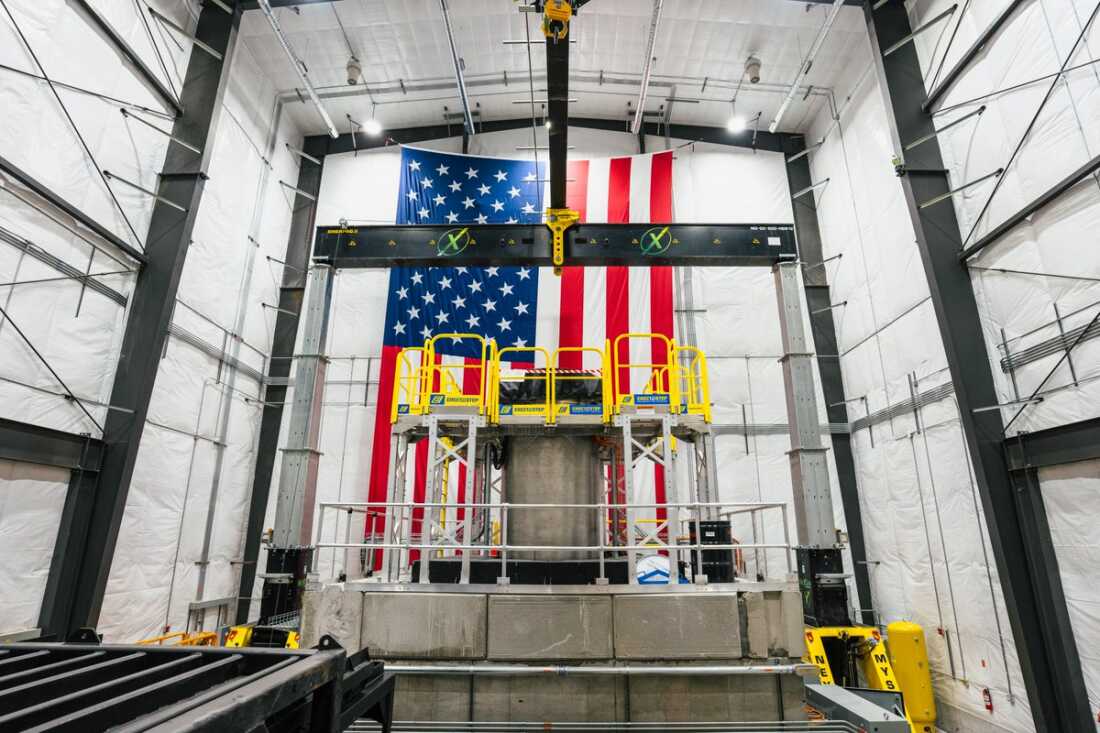 Aalo Atomics' Aalo-X Critical Test Reactor stands inside the company's facility in Idaho Falls, Idaho. A large American flag hangs vertically on the facility's back wall.
