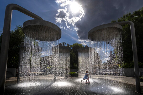 A girl cools off in a public fountain in Vilnius, Lithuania, Friday, June 26, 2026. (AP Photo/Mindaugas Kulbis)