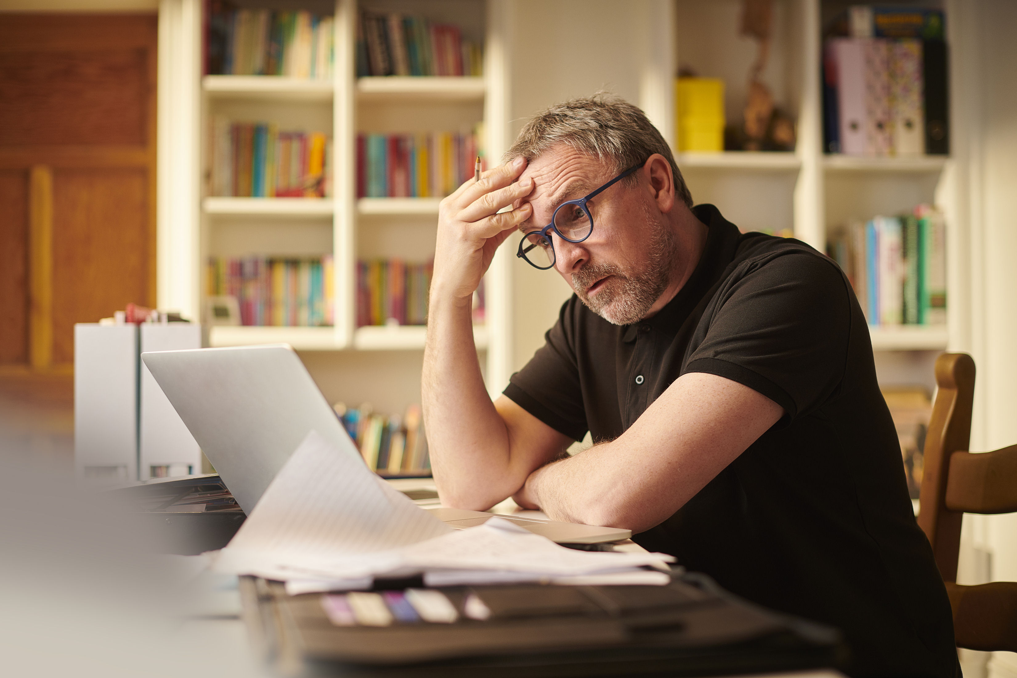 A stressed retiree is staring at a laptop screen.