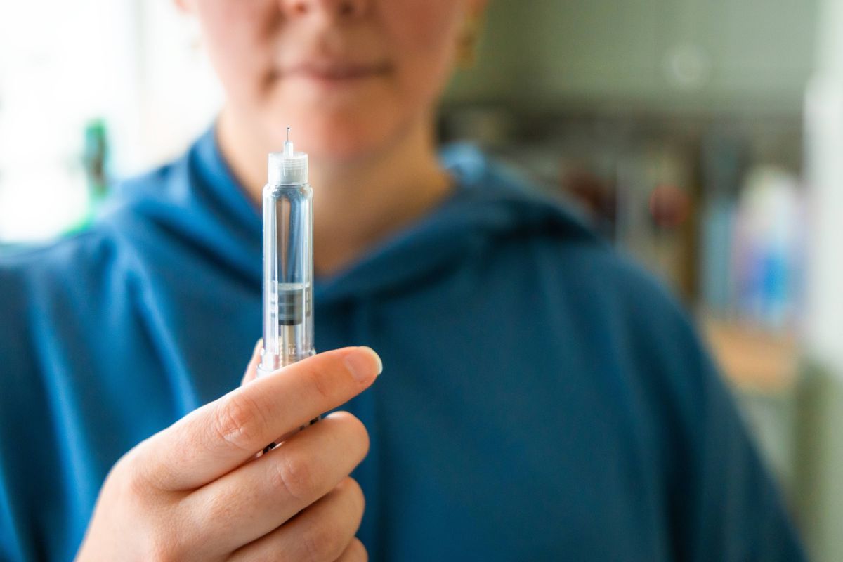 Close up of a woman's hands holding an injection pen