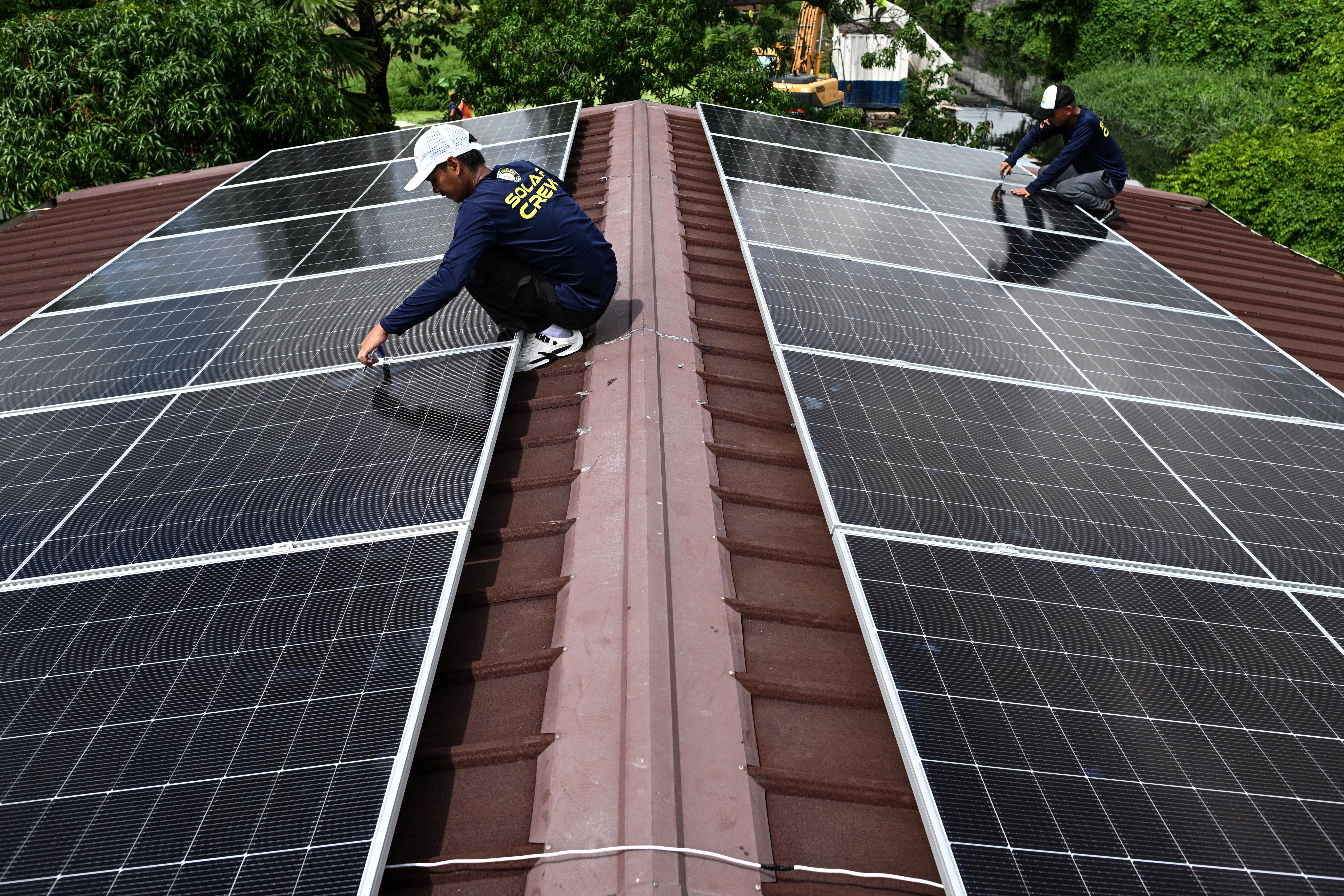 Workers install solar panels on the roof of a house in Kawit, Philippines