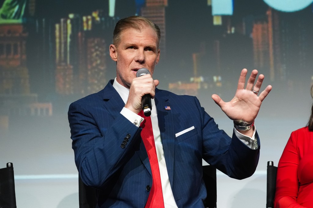 Former football player Greg Olsen speaks into a microphone at the Fox Sports FIFA World Cup 2026 media day.