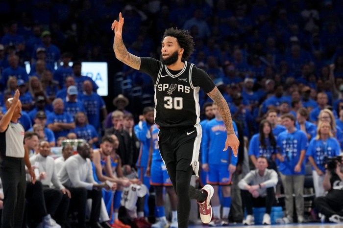 Julian Champagnie holds one arm up and celebrates during the game