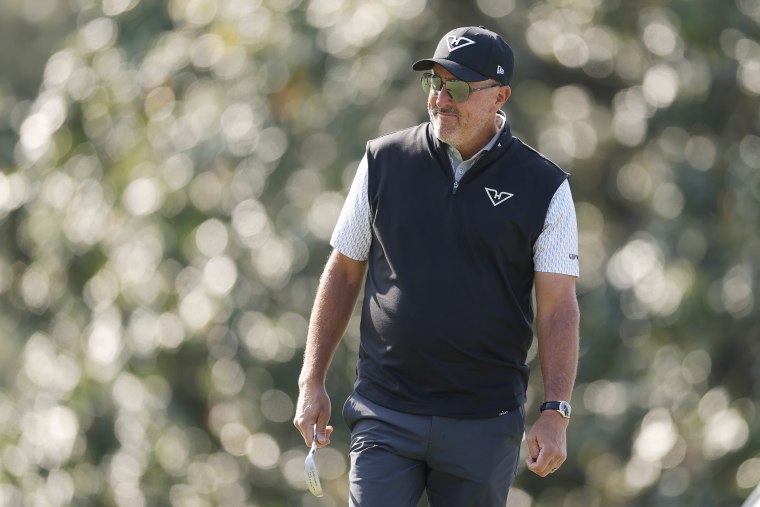 Phil Mickelson standing on a golf course wearing sunglasses against a blurred background.