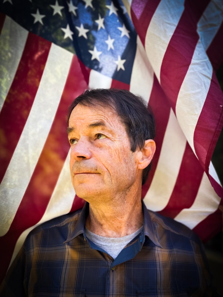 Bruce Watson stands in front of an American flag