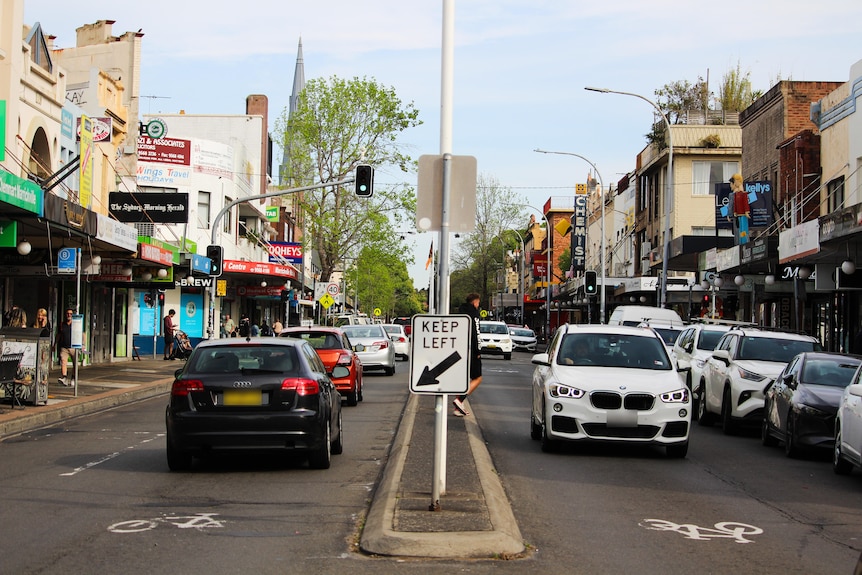 two cars on the road with a keep left sign on marrickille road
