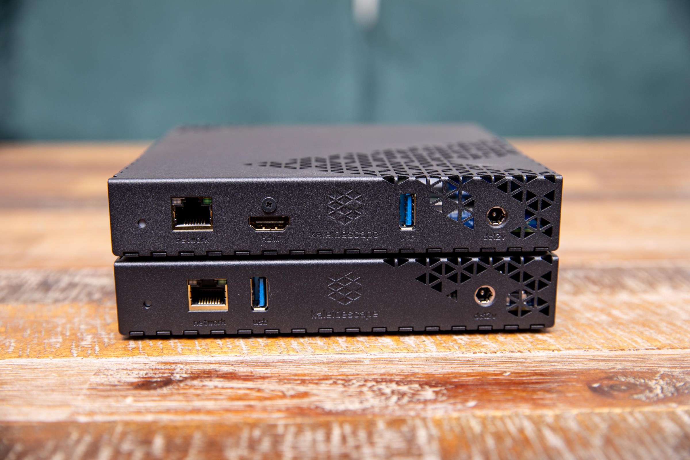 A closeup of the back connections on the Kaleidescape Strato E and Mini Terra Prime server, stacked on a wooden table.