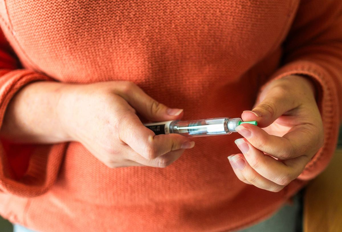 Close up of a woman's hands holding a weight loss injection syringe.