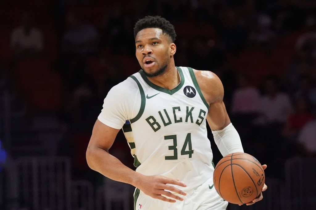 Giannis Antetokounmpo dribbling the ball in a white Bucks jersey with the number 34.