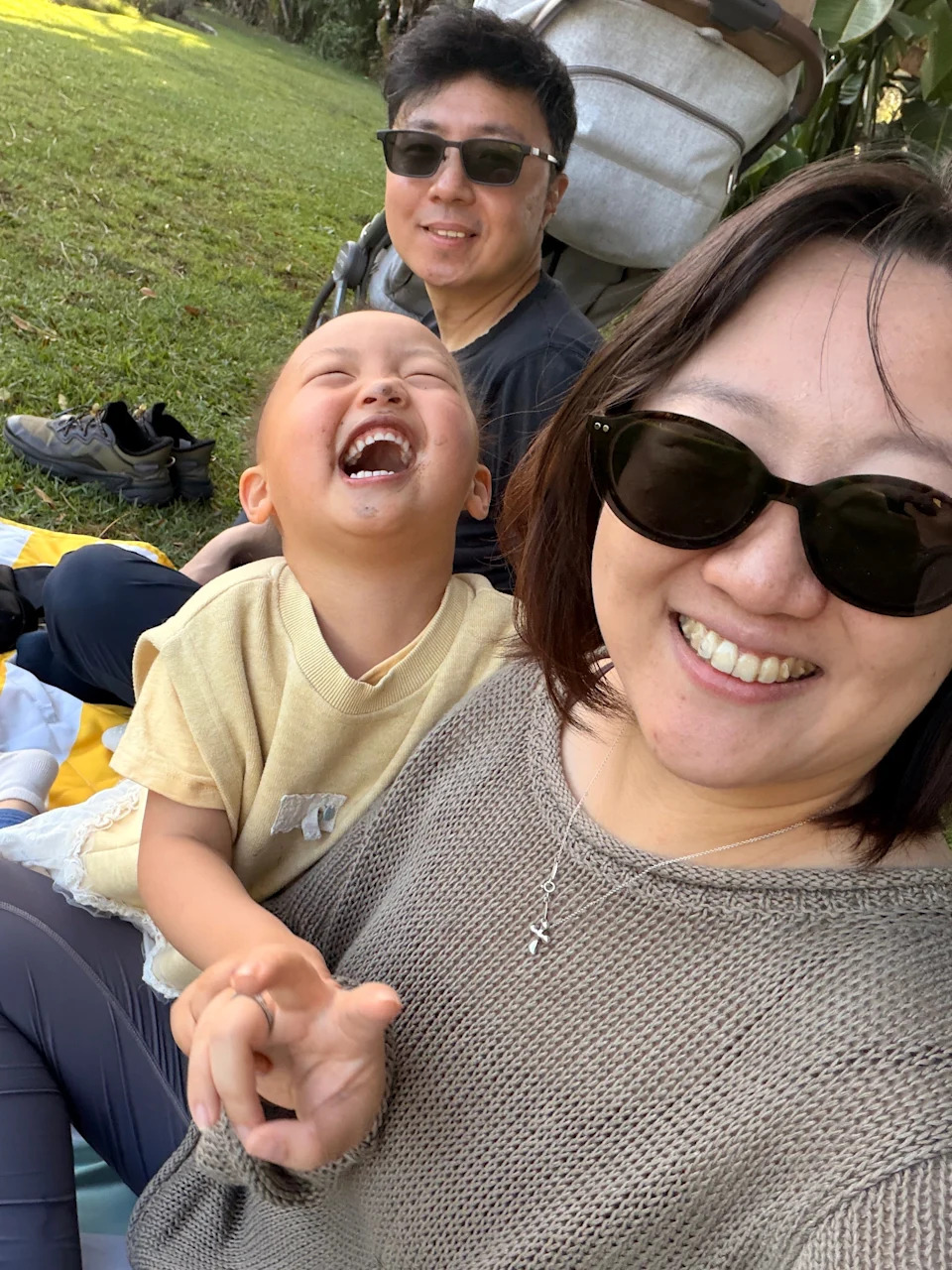 Family of three sitting on the grass in California.