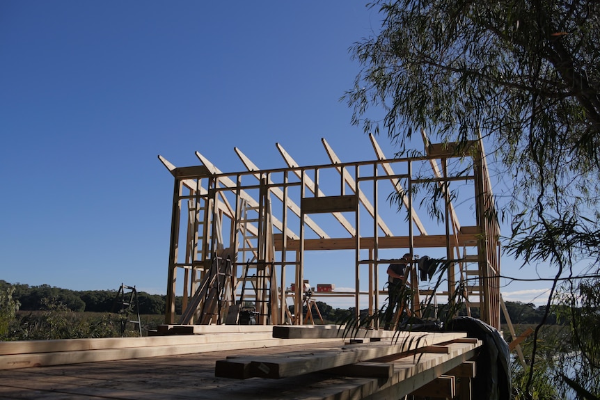 A man stands behind some timber frame.
