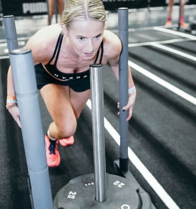 Person pushing a sled with weights on a gym track. Person pushing a sled with weights on a gym track.