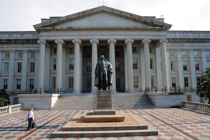 A large courtyard in front of a huge stone building with Ionic columns.