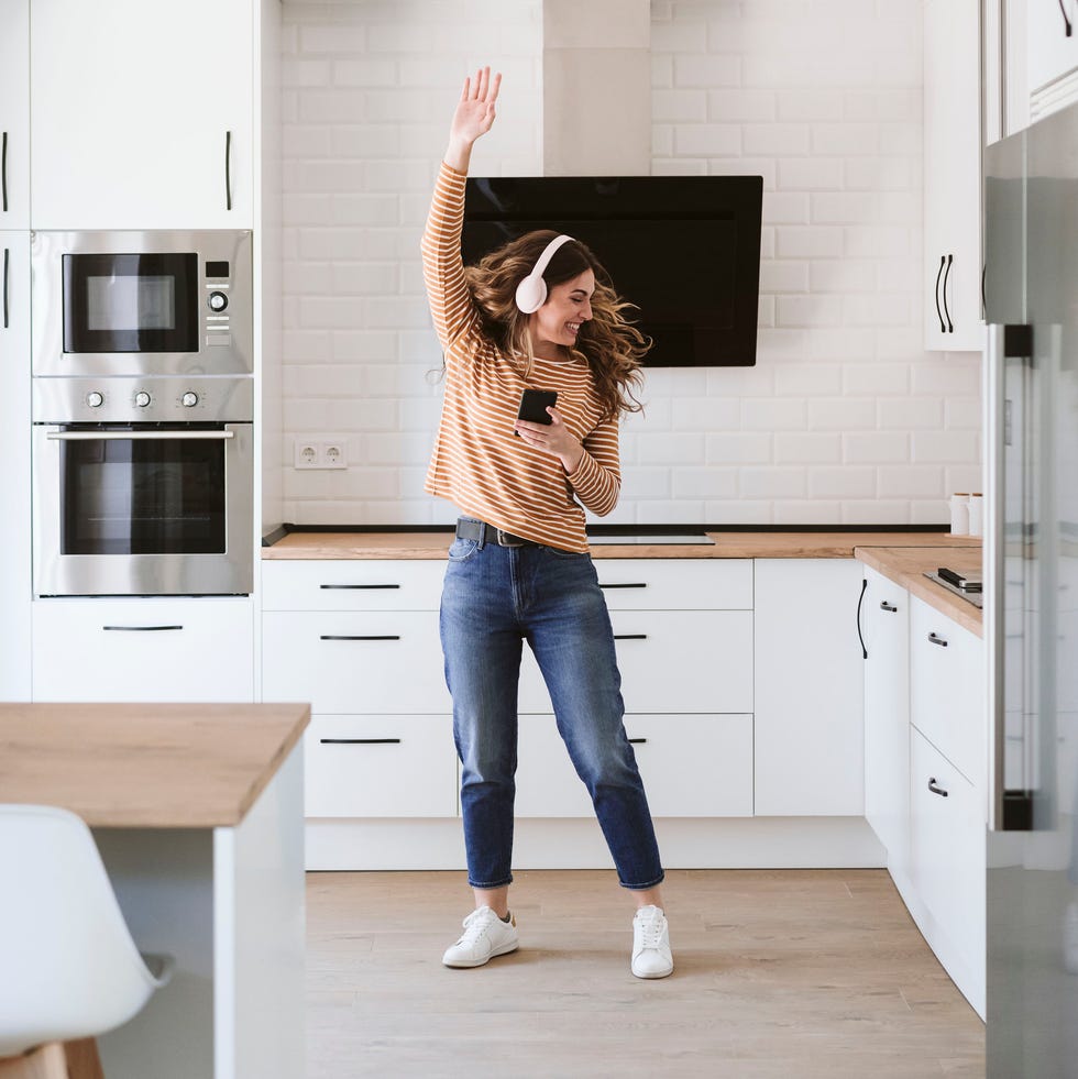 woman listening to music in kitchen at home