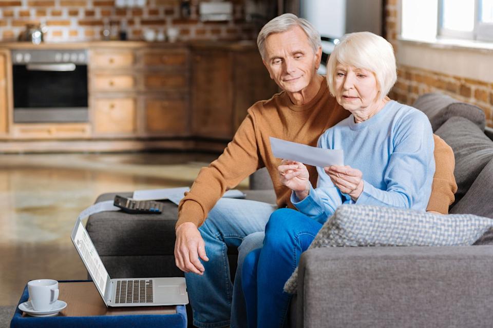 Couple sitting on the couch, examining a check. 