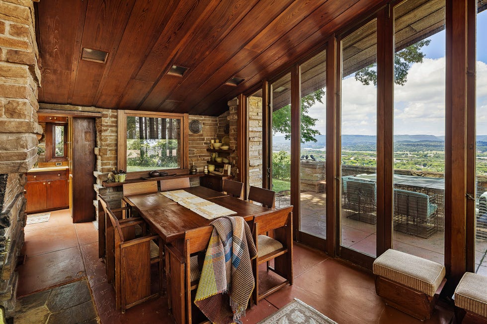 Interior view of a dining area showcasing wooden furniture and large windows overlooking a scenic landscape.