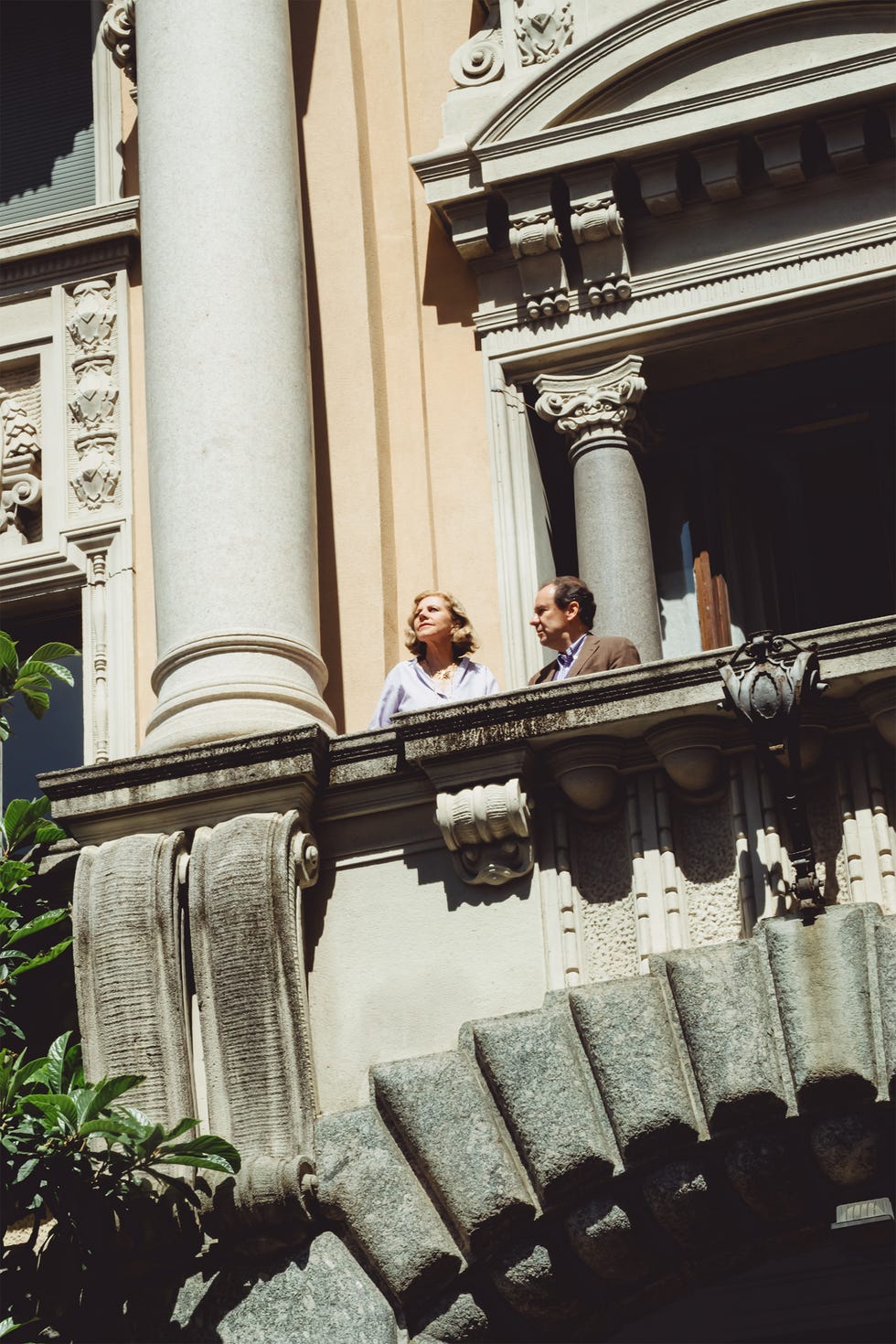 Two people standing on an ornate stone balcony.