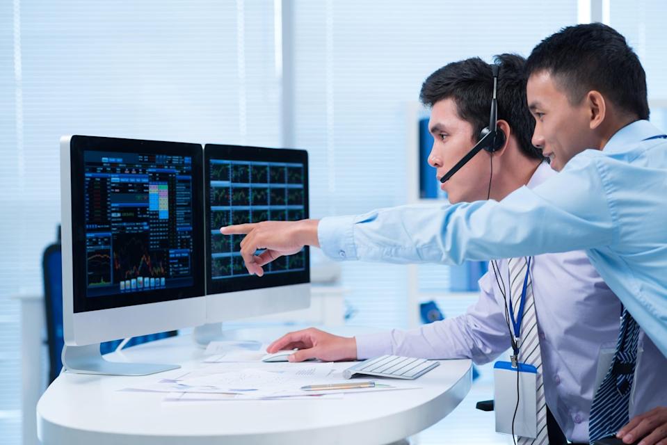 Two people looking at computer, with one pointing at it.
