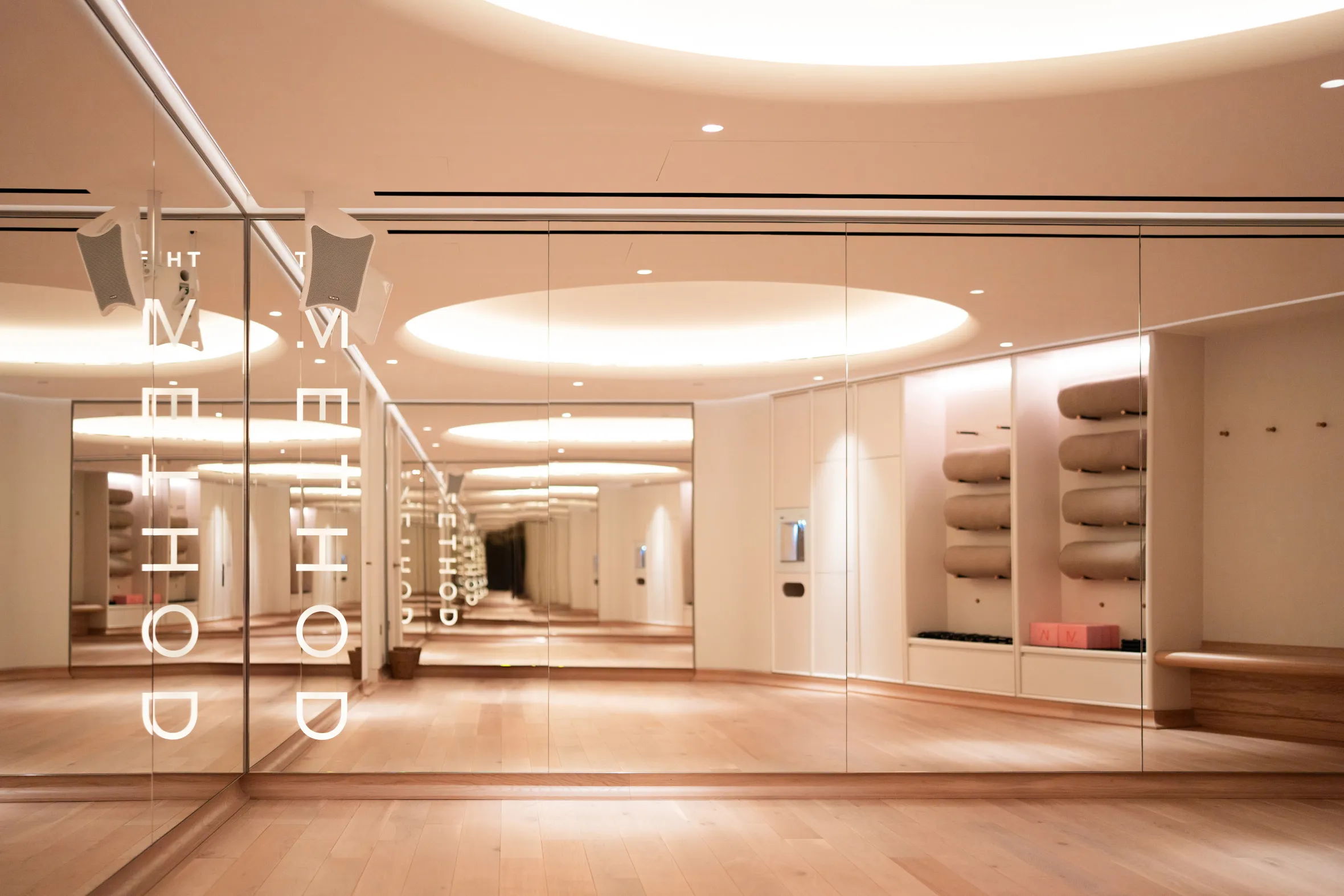 A spacious fitness studio with wooden floors and mirrored walls. The words "THE METHOD" are visible on the mirrors.