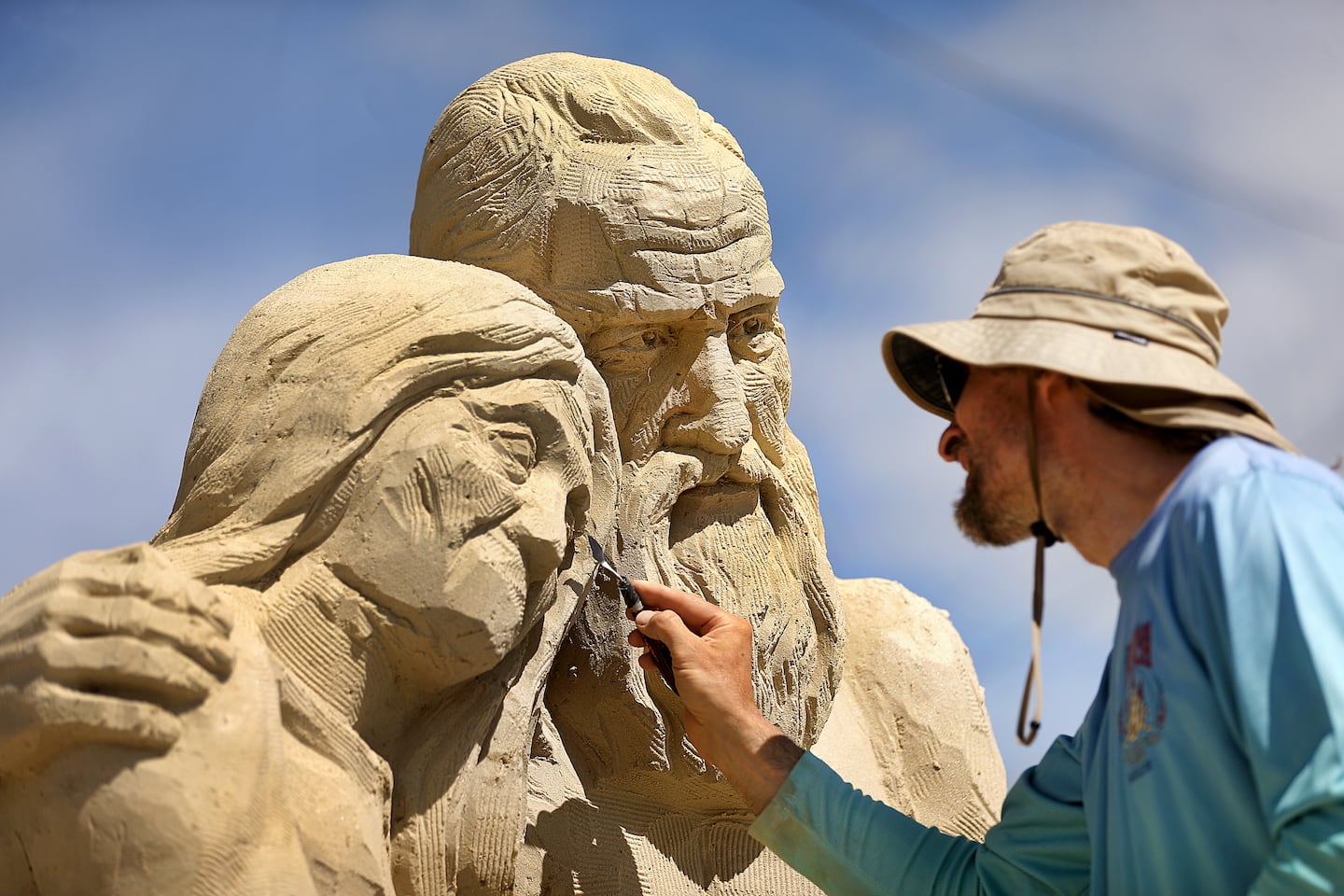 Karlis Ile from Riga, Latvia, carves detail into a face of his sand sculpture called "Waiting for Sunrise" in Hampton Beach, N.H., on Saturday, June 20, 2026.
