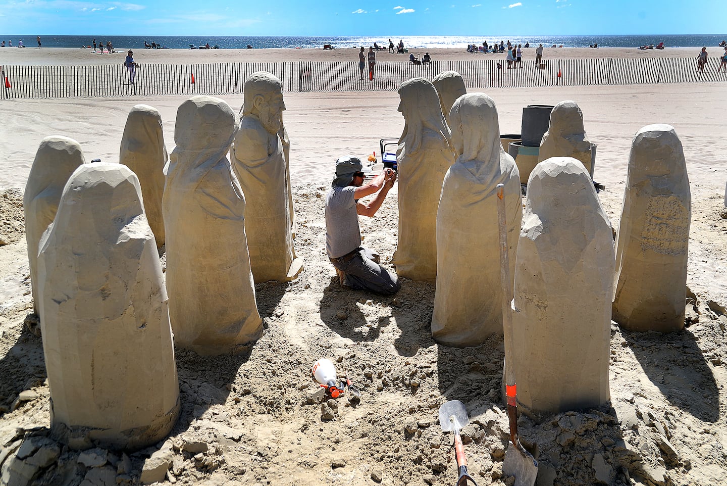 Carl Jara from Lyndhurst, Ohio, is surrounded by carved figures as he works on his sand sculpture called "Ancestral Knowledge."