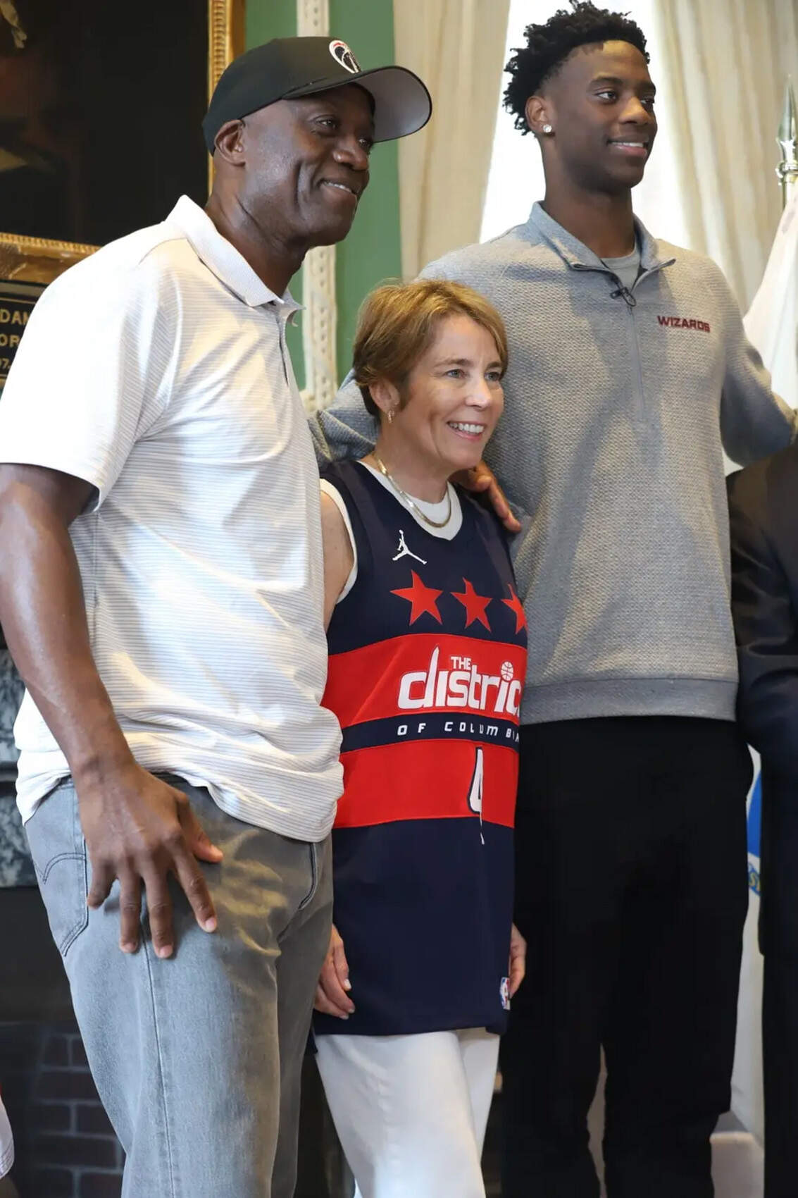Gov. Maura Healey (center) stands between No. 1 NBA 2026 draft pick AJ Dybantsa (right) and his father, Ace Dybantsa (left), in her State House office on June 29, 2026.(Ella Adams / SHNS)