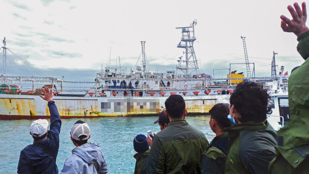 Fishers wave from onboard a Chinese-flagged squid jigger. Credit: Environmental Justice Foundation