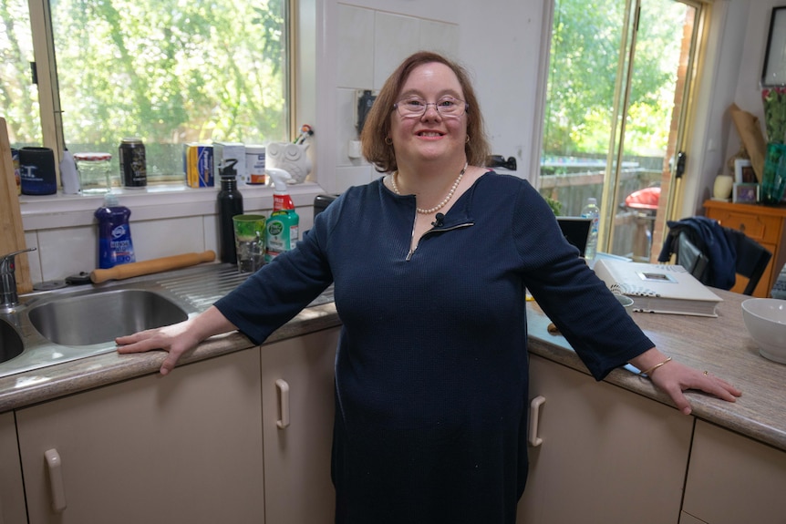 A woman wearing business attire stands in a hospital corridor