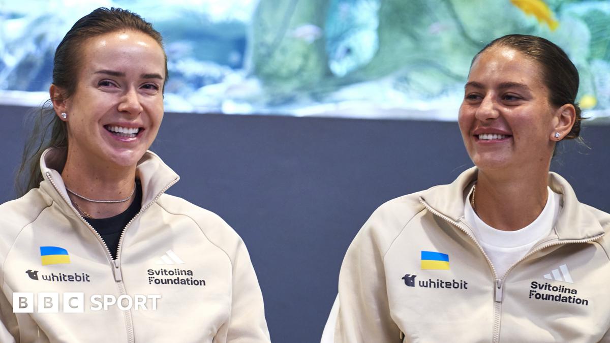 Elina Svitolina and Marta Kostyuk sit together and smile wearing cream zip-up jackets