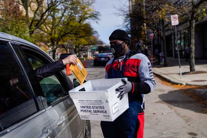 United States Election 2020 Michigan DETROIT, MI - NOVEMBER 02: Jovun Perry, 28, of Detroit collects ballots from drivers as cars line up as voters drop off their ballots or vote in person at the City of Detroit Dept. of Elections office on Monday, Nov. 2, 2020 in Detroit, MI. With only a day remaining before the U.S. election and an unprecedented early voting turnout, President Donald Trump and Democratic nominee former Vice-President Joe Biden are campaigning in crucial swing states. (Kent Nishimura / Los Angeles Times via Getty Images)