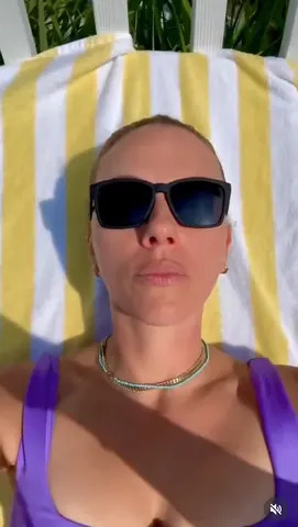 Scarlett Johansson shows off her makeup-free skin while lounging in a purple swimsuit in a video shared to The Outset's Instagram account on June 25, 2026.Credit: The Outset/Instagram