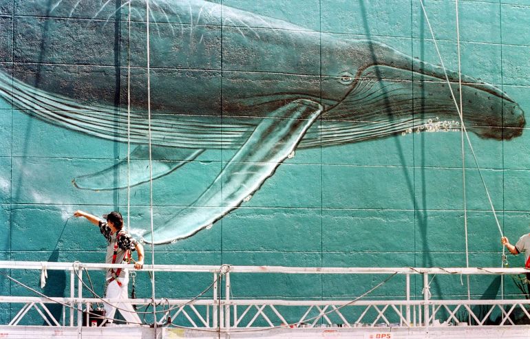 Marine life artist Wyland uses a small brush to put the finishing touches to his rendition of a humpback whale in a seven-story-high mural depicting marine mammals in the ocean in downtown Miami 30 April. Wyland, who has been painting whale and other marine mammal murals since 1981 and has completed 77 walls throughout the US, Japan, Australia, Mexico and France, is currently on a 30-year project to complete 100 marine life murals by the year 2011 in an effort to increase support for the preservation of the ocean. AFP PHOTO Roberto SCHMIDT (Photo by ROBERTO SCHMIDT / AFP)