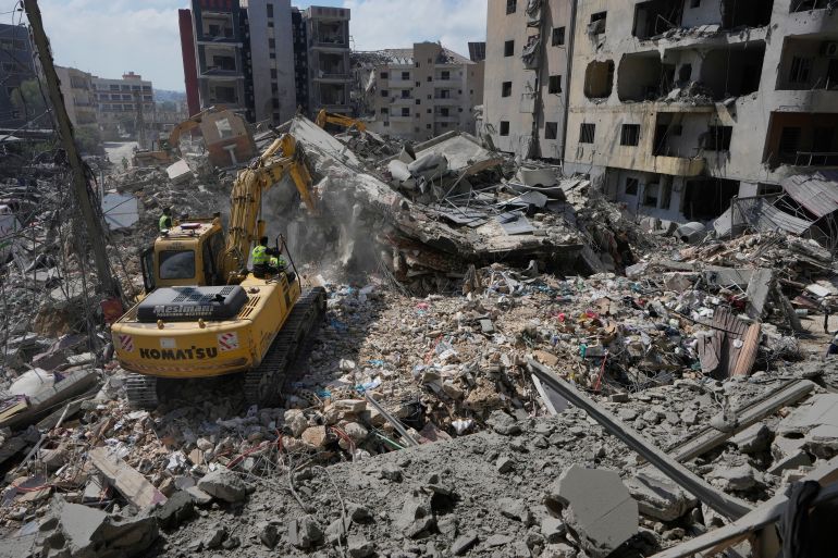 Rescue workers use an excavator, as they search for victims under the rubble of a building