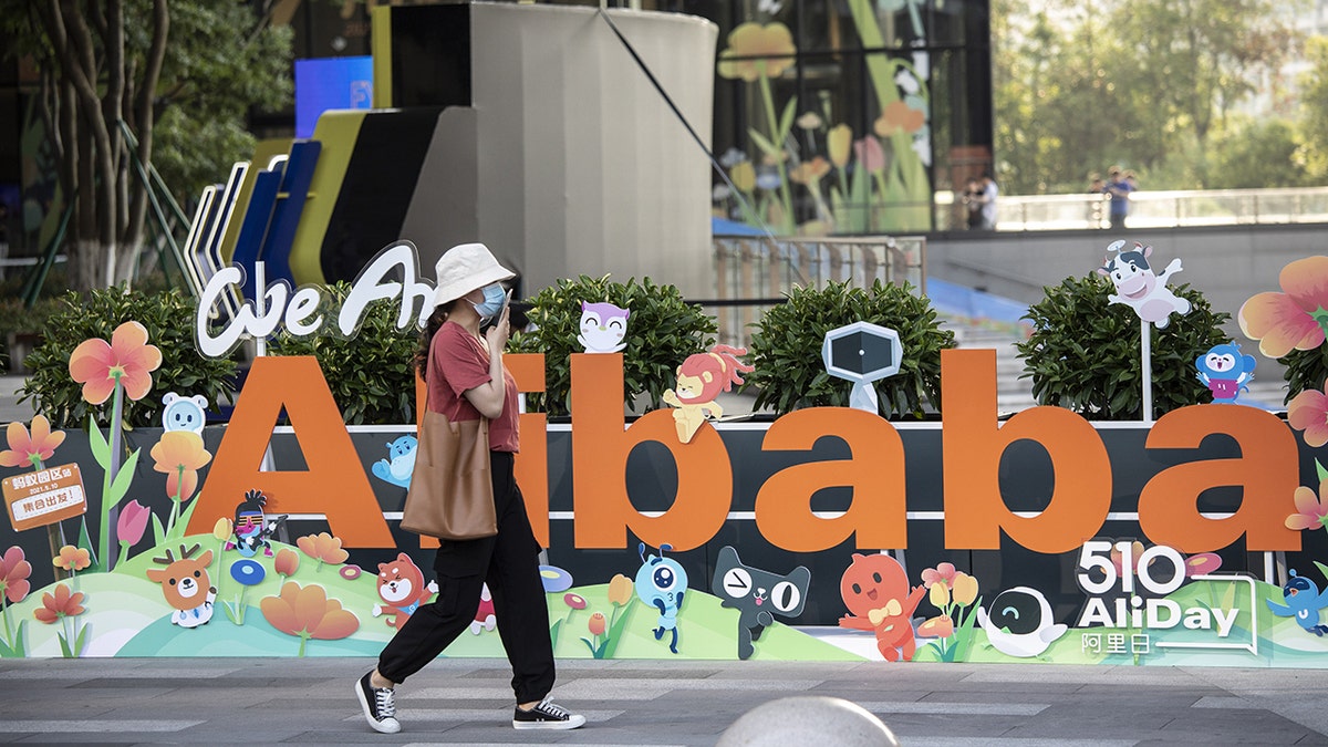 A person walking past a sign at Alibaba Group Holding Ltd. headquarters in Hangzhou China