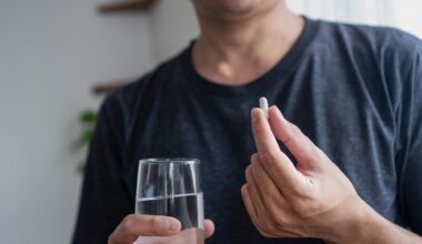 Asian Man Taking Supplement Capsule Pill With Water