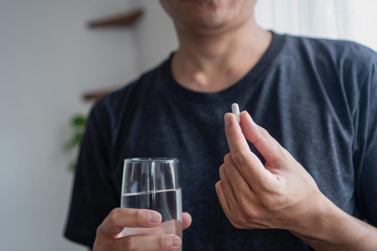 Asian Man Taking Supplement Capsule Pill With Water