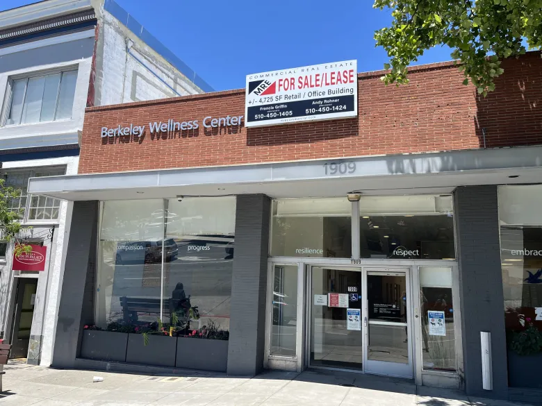The exterior of a one-story commercial building with a "for sale/lease" sign