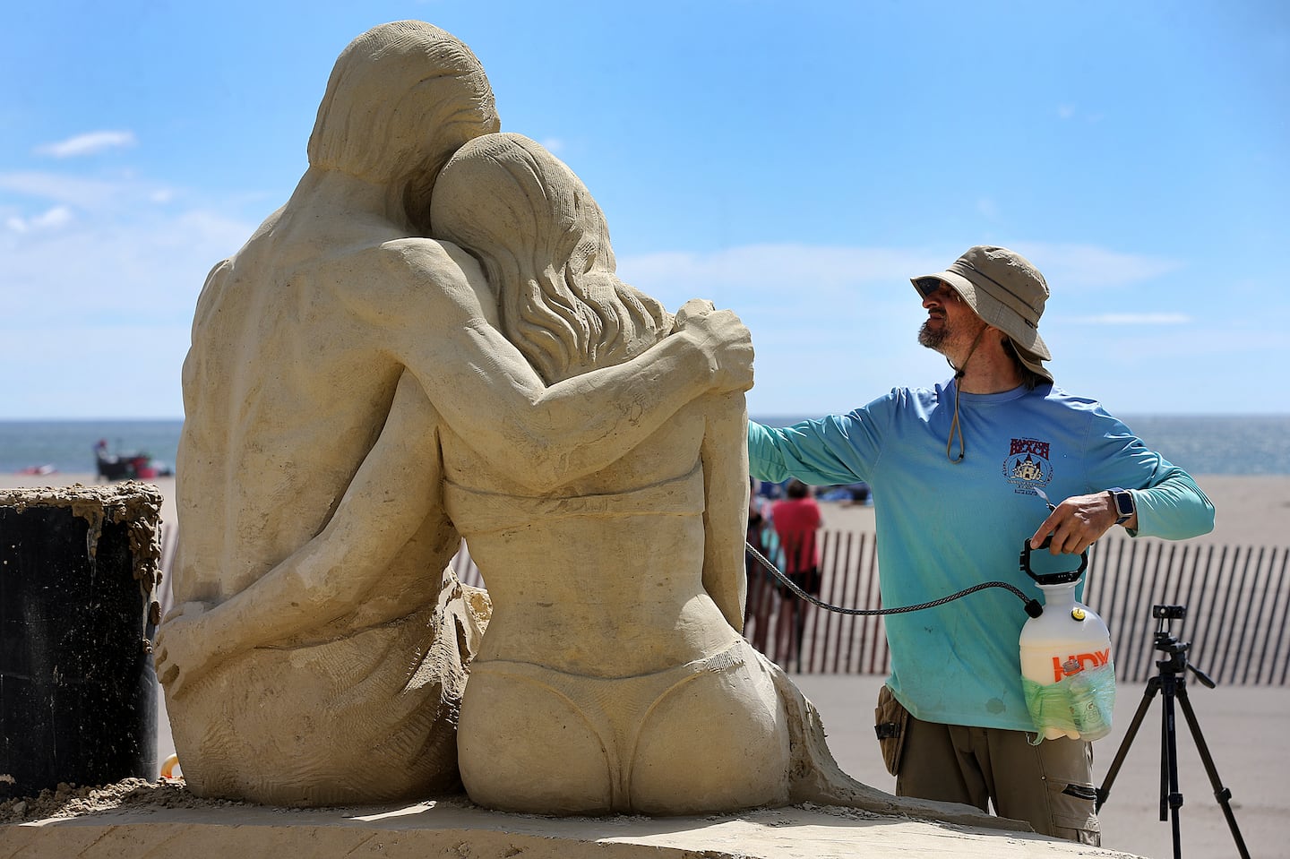 Karlis Ile from Riga, Latvia,  sprays water to wet the sand as he works on his sand sculpture called "Waiting for Sunrise" during the 26th Annual Hampton Beach Master Sand Sculpting Classic.