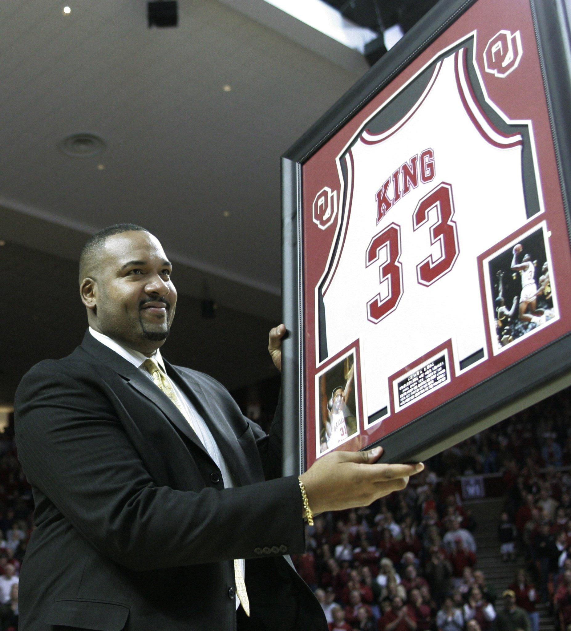 Former University of Oklahoma All-American Stacey King holds a framed...