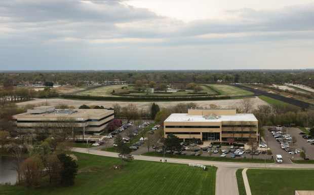 Vehicles are parked in office building lots west of the former Arlington International Racecourse, April 21, 2026, in Arlington Heights. The vacant land is the possible future site of a new stadium for the Chicago Bears. (John J. Kim/Chicago Tribune)
